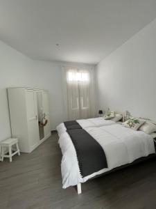 a white bedroom with a large bed and a window at Meriga in Agulo
