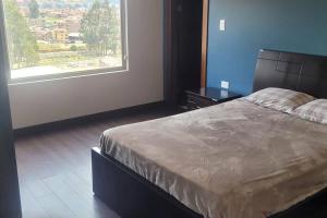 1 dormitorio con cama grande y ventana grande en Departamento Expectacular en Cuenca