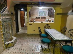 a dining room with a table and chairs and a kitchen at Riad Nezha in Marrakech