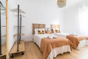 Habitación con 2 camas, paredes blancas y suelo de madera. en Moderno apartamento céntrico en Santander