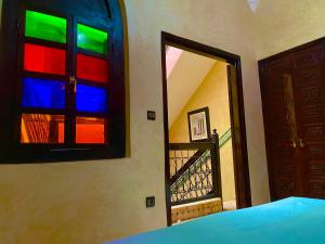 a bedroom with colorful windows and a door with a staircase at Riad Nezha avec piscines jacuzzi parking à quelques minutes à pied du centre-ville in Marrakesh