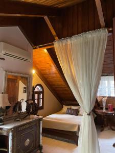 カラブリタにあるPorfyra Luxury Guesthouseのベッドルーム1室(カーテンとテーブル付きのベッド1台付)