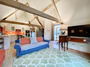 ein Wohnzimmer mit einem blauen Sofa und einem Flachbild-TV in der Unterkunft Bushton Barn in Royal Wootton Bassett