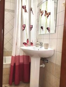 baño con lavabo y cortina de ducha con mariposas en Omonias Apartments en Kavala