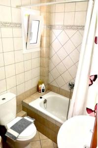 y baño con aseo, bañera y lavamanos. en Omonias Apartments en Kavala