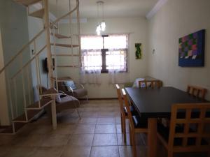 a living room with a table and chairs and a staircase at Apartamento Duplex a 100 metros da Praia de Boracéia in Bertioga