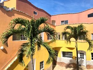 un bâtiment avec des palmiers en face de celui-ci dans l'établissement Eco Hotel Katarma, à Puerto Baquerizo Moreno