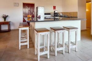 a kitchen with three bar stools and a counter at Hole in the Wall - Unit 47 in Coffee Bay