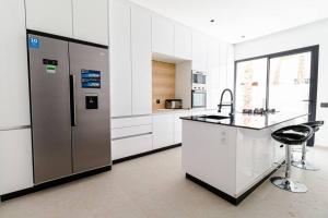a kitchen with white cabinets and a stainless steel refrigerator at Marrakech villa avec piscine privée 4 chambres 4 salles de bains in Marrakesh