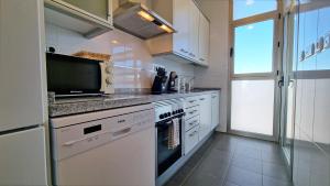 a kitchen with a stove and a microwave at Gran terraza privada con vistas al mar - planta 30 in Benidorm