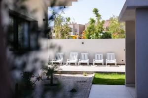 a group of white chairs sitting next to a wall at Marrakech villa avec piscine privée 4 chambres 4 salles de bains in Marrakesh