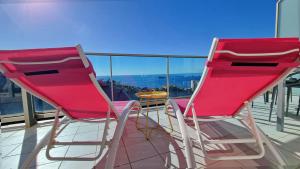 2 sillas rojas y una mesa en el balcón en Gran terraza privada con vistas al mar - planta 30 en Benidorm