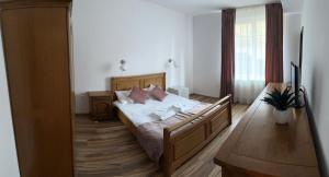 a bedroom with a bed with white sheets and pink pillows at Vila Man in Sovata