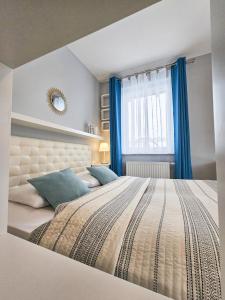 um quarto com uma cama grande e cortinas azuis em APARTAMENTY "LA VILLA" SUPERIOR III z prywatnym ogrodem, tarasem i parkingiem em Kudowa-Zdrój