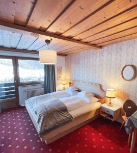 a bedroom with a large bed with a wooden ceiling at Hotel Pradell in Ortisei