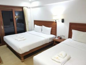 two beds in a hotel room with towels on them at Phuket Meet Holiday Hotel 普吉岛相遇酒店 in Rawai Beach