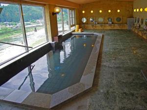 a swimming pool in a building with a large window at Gero Onsen Yukyunohana in Gero