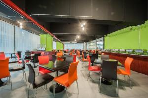 a restaurant with orange and black chairs and tables at The Seasons Bangkok Huamark in Bangkok
