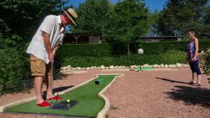 un homme jouant au golf avec un minigolf dans l'établissement Camping Les Lacs de Courtès, à Estang