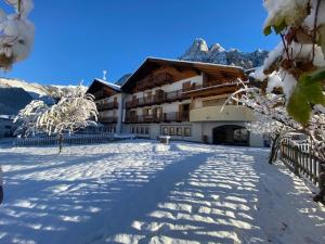 un grande edificio con neve sul terreno di FORESTO - holiday apartments a Tesero