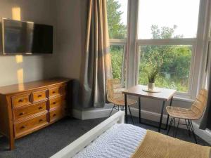 Sleightholme的住宿－Serviced Apartment- 1 Bed-Next To Train Station，一间卧室配有一张床、一张桌子和一个窗户。