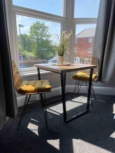 Sleightholme的住宿－Serviced Apartment- 1 Bed-Next To Train Station，窗前的一张桌子和两把椅子