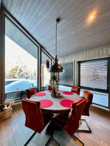 una sala da pranzo con tavolo, sedie e finestre di New cabin near X Country ski trails at Blefjell with Jacuzzi a Flesberg