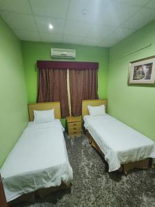 two beds in a room with green walls at منتجع الريحانه فله رقم 1 in Taif
