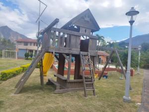 un parque infantil de madera con un tobogán y una honda en Casa vacacional, en Loja