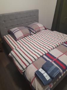 a bed with a striped blanket and two pillows at Lux na Osipenko in Uzhhorod