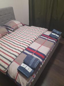 a bed with a striped comforter with towels on it at Lux na Osipenko in Uzhhorod