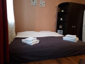 Una cama con toallas blancas encima. en M&A Mario Ultra Central Apartament, en Brasov