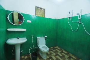 a green bathroom with a toilet and a sink at Sigiri Green Shadow Homestay in Sigiriya