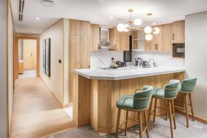 a kitchen with wooden cabinets and green bar stools at Taiba Suites Madinah in Al Madinah