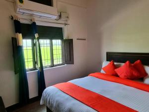 Schlafzimmer mit einem Bett mit roten Kissen und einem Fenster in der Unterkunft Jim Corbett Home stay in Jhirna