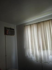 a room with a window with a fan and a window curtain at Apto 2px.unesc in Criciúma