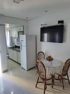 cocina con mesa y nevera blanca en Bahia Flat 301, en Salvador