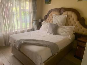 1 dormitorio con 1 cama grande con sábanas y almohadas blancas en The Crown Inn Guest House, en Harare