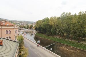 een uitzicht op een rivier vanuit een gebouw naast een straat bij Latin Apartment in Sarajevo