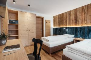 a hotel room with two beds and a desk at Residence Villa Trieste in Corvara in Badia