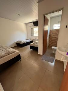 a bedroom with two beds and a sink and a bathroom at HOTEL ARIZON in Inocência