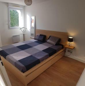 a bedroom with a large bed with a blue and white checkered mattress at Résidence avec Parking et piscine - Proche airport in Blagnac