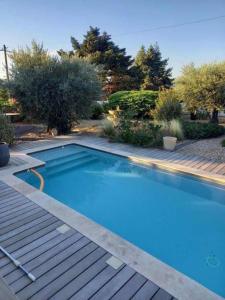 een groot blauw zwembad naast een houten terras bij Maison avec piscine in Villeneuve