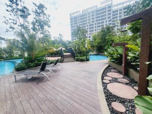 eine Holzterrasse mit Stühlen und einem Pool in der Unterkunft Gaia Residences, Gamuda Garden, 3 min to Skyline Luge in Rawang