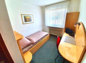 een kleine kamer met een bed en een bureau bij Pension Alex in Bielefeld