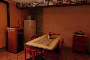 cocina con mesa con sillas rojas y nevera blanca en Di Baut, en Ovaro