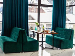 two green chairs and a table in a room at Mirage in Bukovel
