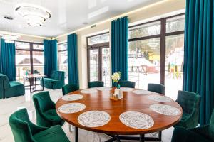 a dining room with a wooden table and green chairs at Mirage in Bukovel