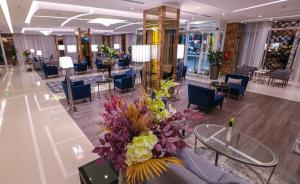 ウナイザにあるفندق شيرفل الواحة عنيزة Cheerful Al Waha Unayzah Hotelのホテルのロビーにはテーブルと椅子があり、花を飾っています。