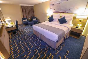 فندق شيرفل الواحة عنيزة Cheerful Al Waha Unayzah Hotel في عنيزة: غرفة فندقية بسرير كبير وكرسي
